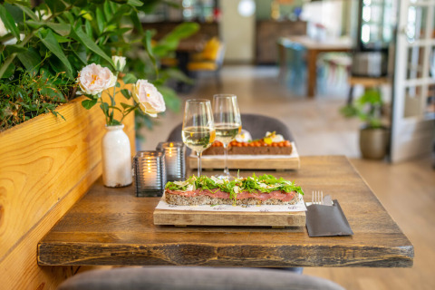 Et hyggeligt bord med smørrebrød, vin, blomster og levende lys på Gooise Heide feriepark i Holland.