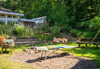 Udendørs opholdsområde på Gooise Heide feriepark i Nord-Holland med bænke, farverige puder og natur.