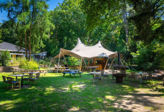 Zona de asientos al aire libre con carpa y vegetación en el parque vacacional Gooise Heide, Holanda Septentrional.