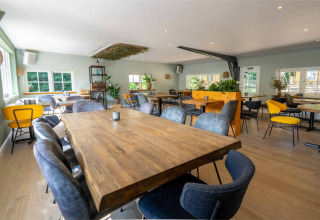 Lyst og rummeligt spiseområde på Gooise Heide feriepark i Nordholland, Holland, med moderne indretning.