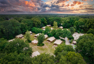 Aerial view of Gooise Heide holiday park in North-Holland, Netherlands, surrounded by lush green forest at sunset.