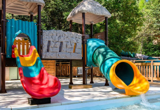 Legeområde med farverige rutsjebaner ved en pool i Flower Camping la Pinède, Auvergne-Rhône-Alpes, Frankrig.