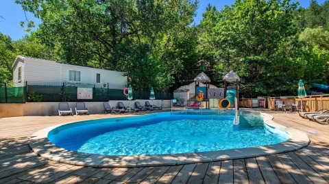 Udendørs swimmingpool med vandrutsjebane og liggestole omgivet af træer på Flower Camping la Pinède i Frankrig.