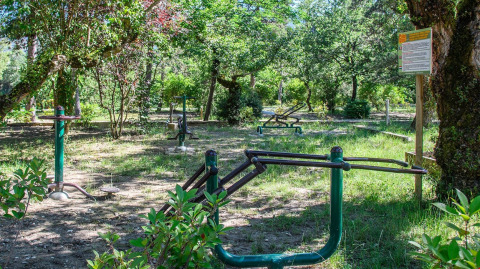 Outdoor gym equipment in a wooded area at Flower Camping la Pinède, Auvergne-Rhône-Alpes, France.
