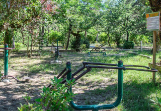 Udendørs fitnessområde i skovklædt park ved Flower Camping la Pinède i Auvergne-Rhône-Alpes, Frankrig.