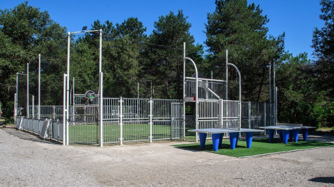 Area sportiva all'aperto con campo recintato e tavoli da ping pong a Flower Camping la Pinède, Auvergne-Rhône-Alpes.