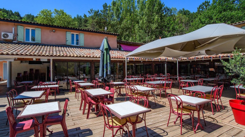 Terrasse extérieure avec tables et chaises au Flower Camping la Pinède, Auvergne-Rhône-Alpes, France.