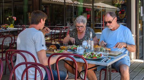 Three people enjoy a meal outside at Flower Camping la Pinède, a holiday park in Auvergne-Rhône-Alpes, France.