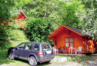 Un SUV nero parcheggiato davanti a un bungalow di legno immerso nel verde al Bedura Park in Spagna.