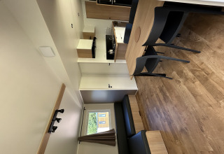 Vista interior de una cabaña moderna en Camping Seasonova Les Marguerites en Francia, con mesa y cocina.