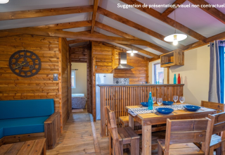 Knus houten lodge-interieur met eet- en keukengedeelte bij Lodge Premium VIP, Flower Camping L'Ile d'Offard.