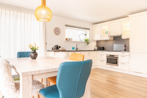 Cucina moderna e luminosa con sala da pranzo a Villa BushBush, De Kremmer, Paesi Bassi, con sedie colorate.