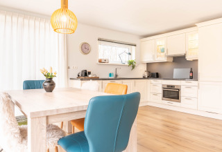 Cucina moderna e luminosa con sala da pranzo a Villa BushBush, De Kremmer, Paesi Bassi, con sedie colorate.