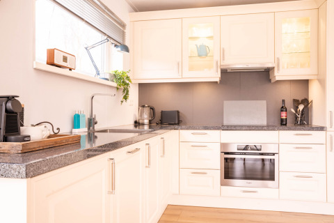 Cucina moderna nella Villa «BushBush» a De Kremmer, Paesi Bassi, con mobili bianchi e elettrodomestici.