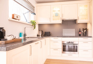 Cucina moderna nella Villa «BushBush» a De Kremmer, Paesi Bassi, con mobili bianchi e elettrodomestici.