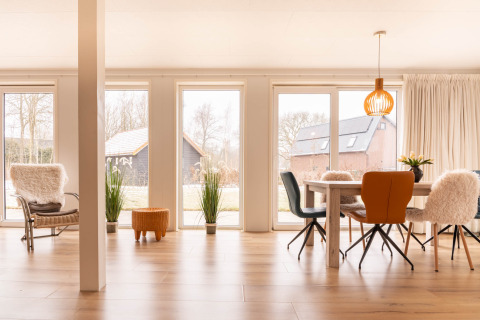 Luminoso soggiorno moderno a Villa BushBush, De Kremmer, Paesi Bassi con grandi finestre e arredo accogliente.