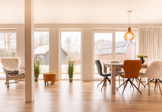Luminoso soggiorno moderno a Villa BushBush, De Kremmer, Paesi Bassi con grandi finestre e arredo accogliente.
