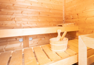 Interno di sauna in legno chiaro con panche e secchio, fotografato a Villa «BushBush» a De Kremmer, Paesi Bassi.