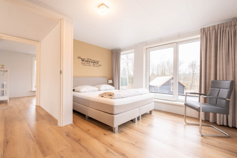Camera da letto luminosa e moderna con letto matrimoniale e grandi finestre nella Villa BushBush, De Kremmer, Paesi Bassi.
