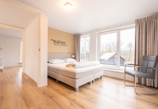 Camera da letto luminosa e moderna con letto matrimoniale e grandi finestre nella Villa BushBush, De Kremmer, Paesi Bassi.