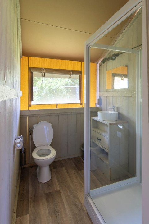 Badezimmer in einem Safarizelt mit Dusche, Toilette und Waschbecken auf Campingplatz De Rammelbeek.