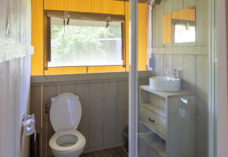 Badezimmer in einem Safarizelt mit Dusche, Toilette und Waschbecken auf Campingplatz De Rammelbeek.