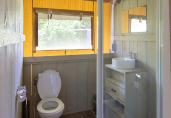 Badezimmer in einem Safarizelt mit Dusche, Toilette und Waschbecken auf Campingplatz De Rammelbeek.