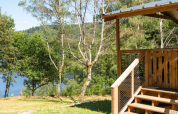 Vista desde la VIP Premium Lodge en Flower Camping La Plage, Francia, con terraza de madera, árboles y lago.