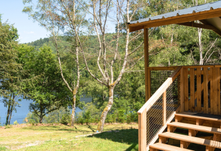 Vista desde la VIP Premium Lodge en Flower Camping La Plage, Francia, con terraza de madera, árboles y lago.