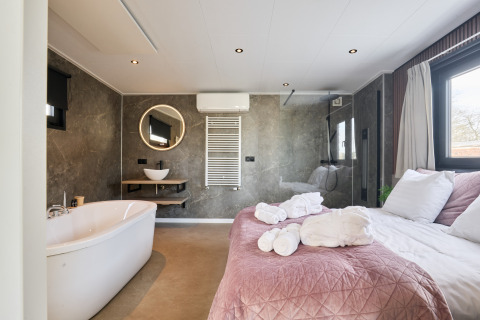Lodge bien-être moderne avec baignoire et lit au Holiday park Mölke, Pays-Bas, pièce lumineuse et élégante.