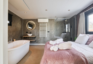 Lodge bien-être moderne avec baignoire et lit au Holiday park Mölke, Pays-Bas, pièce lumineuse et élégante.