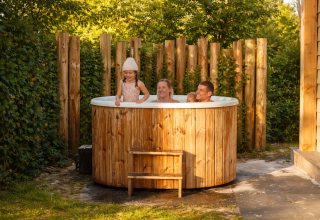 Famiglia si rilassa nella vasca idromassaggio alla Happy Oak wellnesslodge presso Holiday park Mölke, Paesi Bassi.