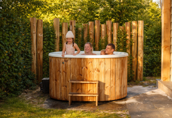 Gezin geniet van een buiten bubbelbad bij Happy Oak wellnesslodge op vakantiepark Mölke in Nederland.