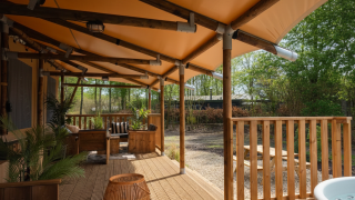 Véranda couverte du lodge safari Cortijo la Perla avec meubles en bois et vue sur la nature.