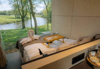 Udsigt fra en seng i River Mirrorlodge på Holiday park Mölke, med panoramaudsigt over floden.