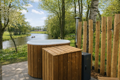 Udendørs badekar ved floden med træpaneler, omgivet af skov ved River Mirrorlodge, Mölke, Holland.