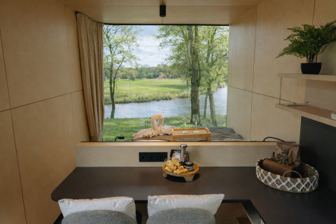 Udsigt fra River Mirrorlodge i Holiday park Mölke, Holland, med flod og grøn natur gennem et stort vindue.