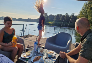 Colazione in famiglia sulla houseboat Marina Mookerplas nei Paesi Bassi, vista sul lago e sole mattutino.