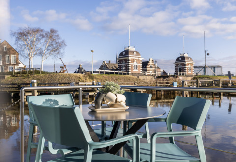 Outdoor table and chairs at Marina Lemmer holiday park, overlooking water and classic buildings in Friesland, Netherlands.