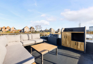 Terrazza con divano e mobili in legno a Marina Lemmer, Friesland, Paesi Bassi, vista sul canale.