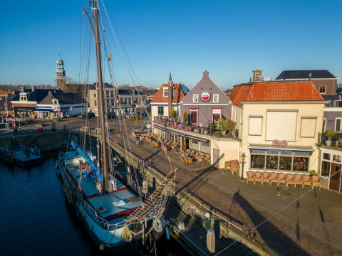 Barcos en Marina Lemmer en Frisia, Países Bajos, con cafés y edificios históricos junto al agua.