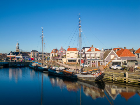 Boten aan de kade bij Marina Lemmer, een vakantiepark in Friesland, Nederland, met huizen en blauwe lucht.