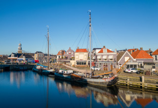 Boten aan de kade bij Marina Lemmer, een vakantiepark in Friesland, Nederland, met huizen en blauwe lucht.