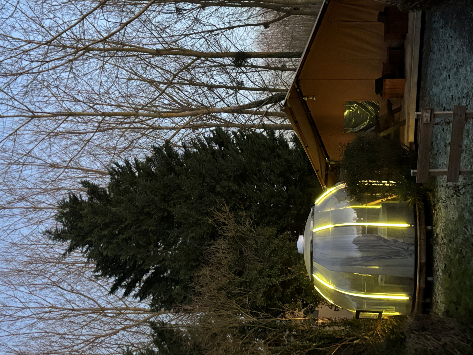 Avondbeeld van Woody Safari Tent met jacuzzi en sfeerverlichting bij Flower Camping de la Trye, Frankrijk.