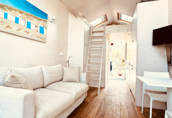 Interno luminoso e moderno di una tiny house in Dishoek, Paesi Bassi, con divano e pavimento in legno.