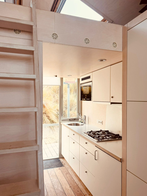 Pequeña cocina moderna en Beach sleep house «Dishoek 37» con escalera de madera y ventanales amplios.