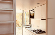 Tiny house kitchen in Beach sleep house «Dishoek 37» with wooden stairs, gas cooktop, and large windows.