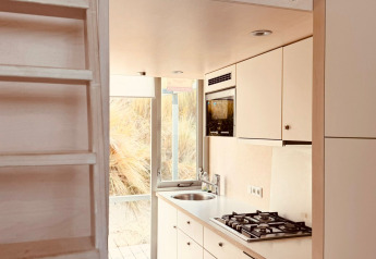 Cucina compatta e moderna al Beach sleep house «Dishoek 37» con scaletta in legno e ampie finestre luminose.