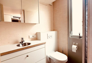 Salle de bain moderne avec toilettes suspendues, lavabo, miroir et sol en bois au Beach sleep house Dishoek, Pays-Bas.