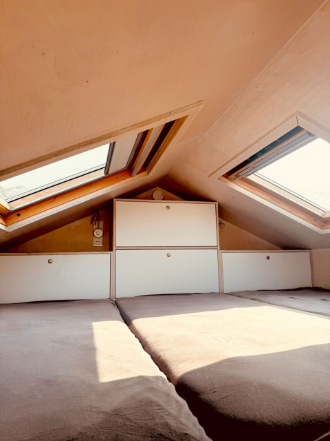 Acogedora zona de dormitorio del desván con tragaluces y almacenamiento en Beach sleep house Dishoek 37, Países Bajos.